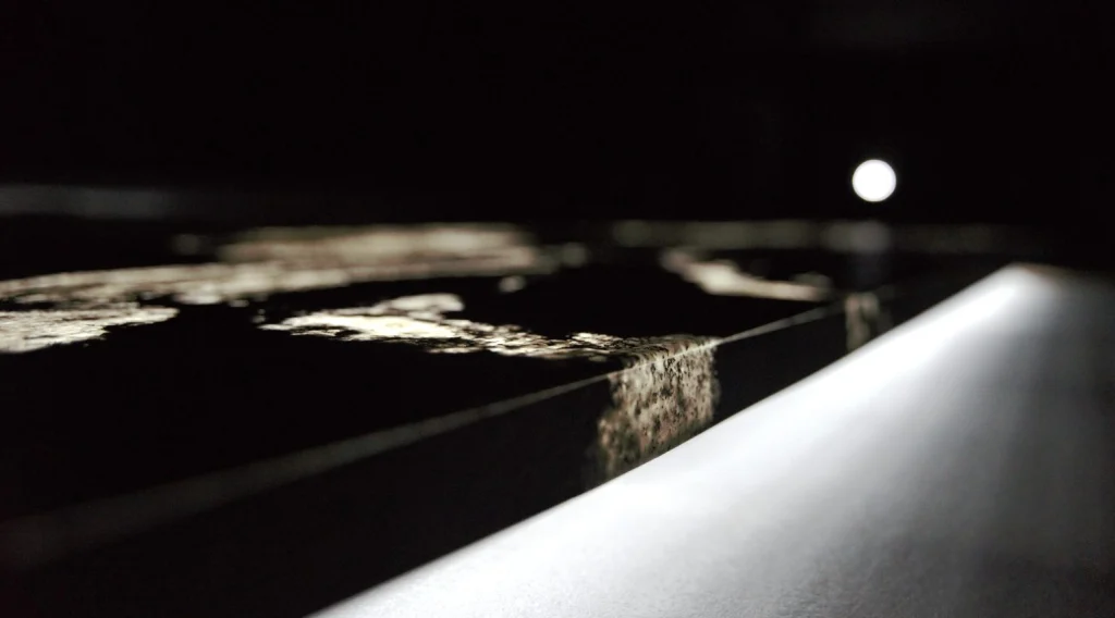 The lit edge of a thin stone panel in the dark